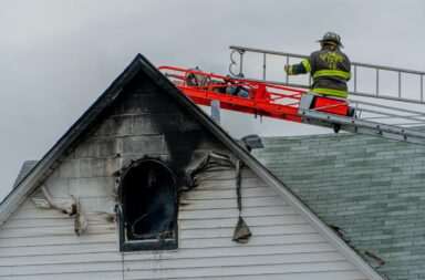 Man on ladder fixing a residential roof in Baltimore city.