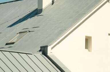 a white house with a metal roof and two chimneys