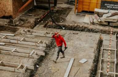 man in red jacket and black pants walking on gray concrete stairs